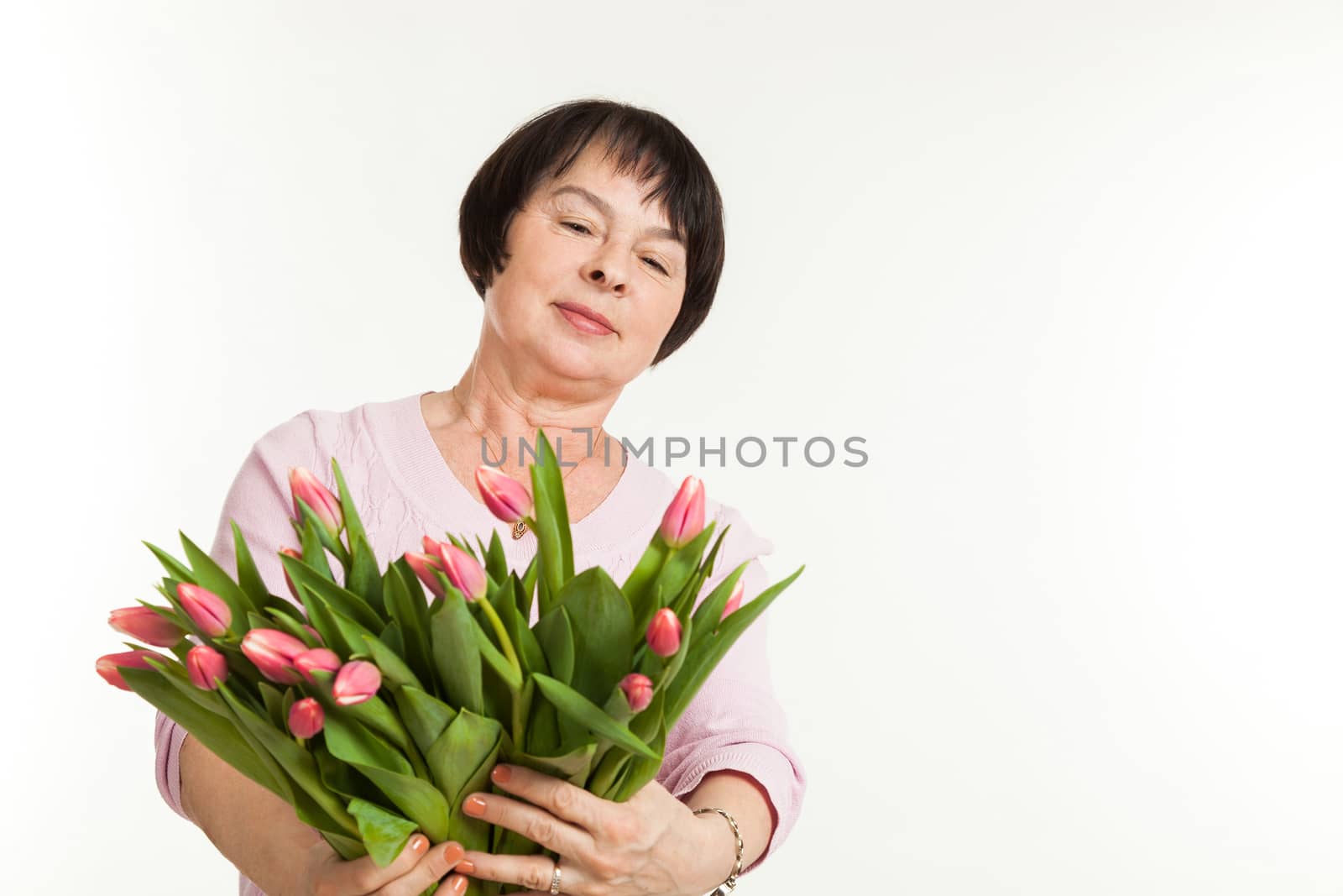 the beautiful mature woman admires to a bouquet of tulips