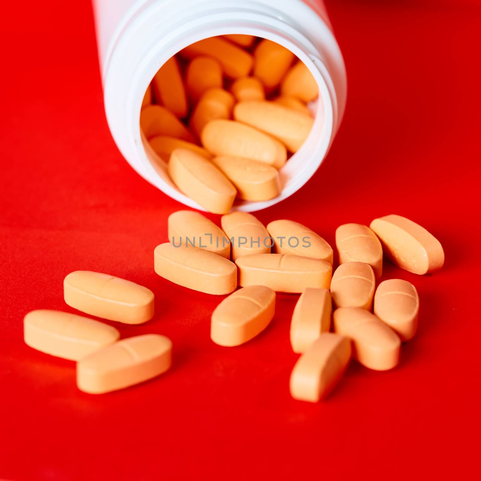 Pills spilling out of pill bottle on red. Top view with copy space. Medicine concept. Shallow dof