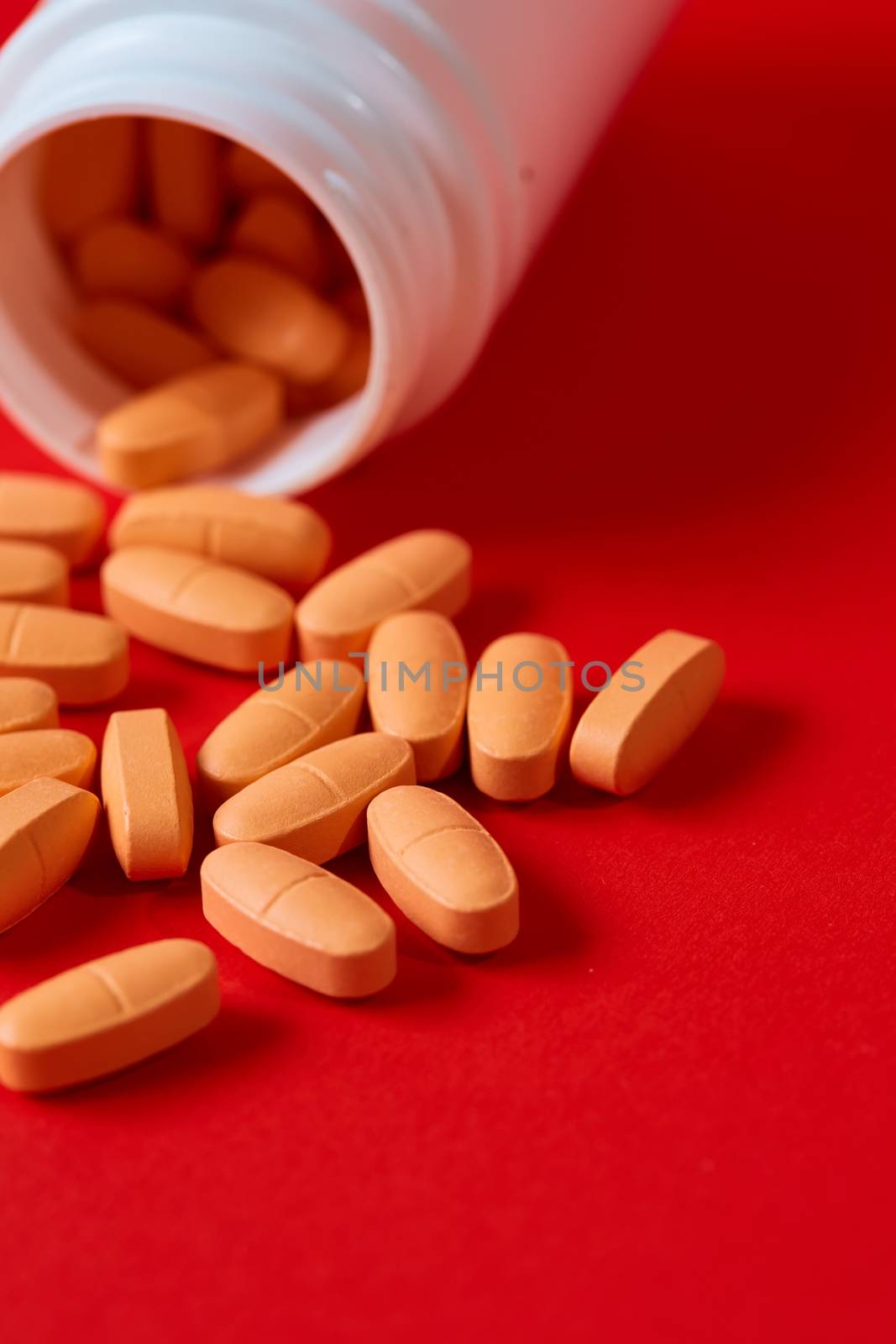 Pills spilling out of pill bottle on red. Top view with copy space. Medicine concept. Shallow dof