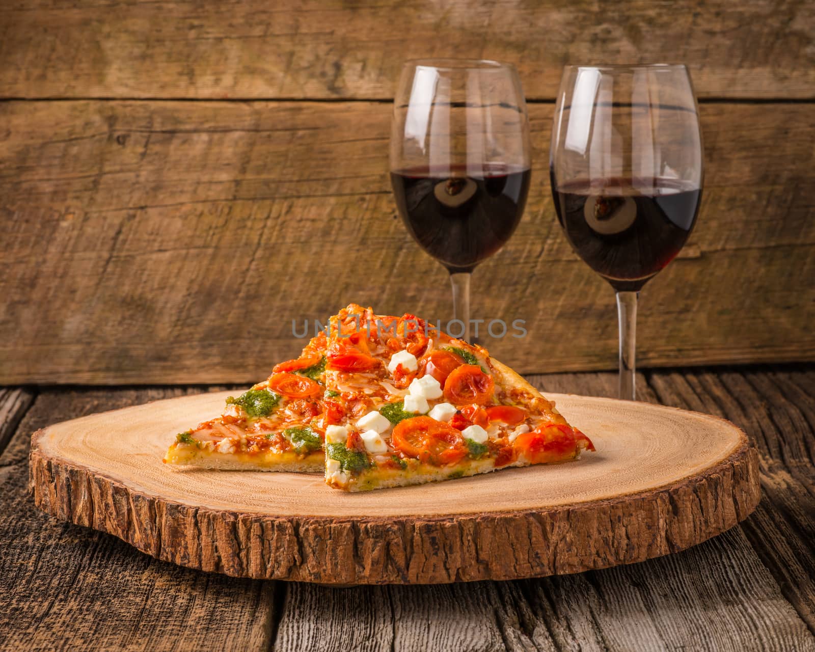 Pizza slices served with glasses of red wine.