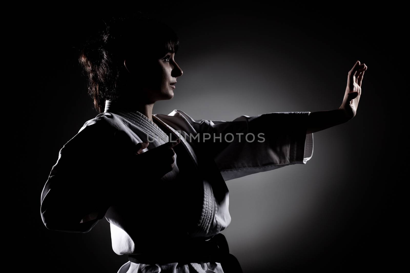 girl exercising karate, against black background