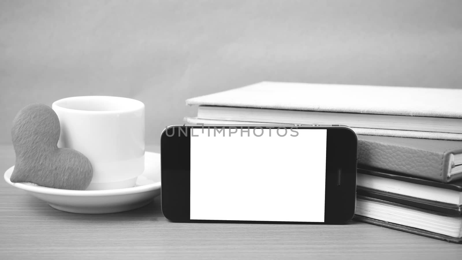 coffee,phone,stack of book and heart on wood table background black and white color
