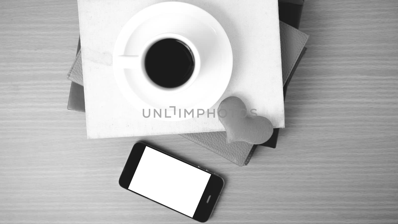 coffee,phone,stack of book and heart on wood table background black and white color