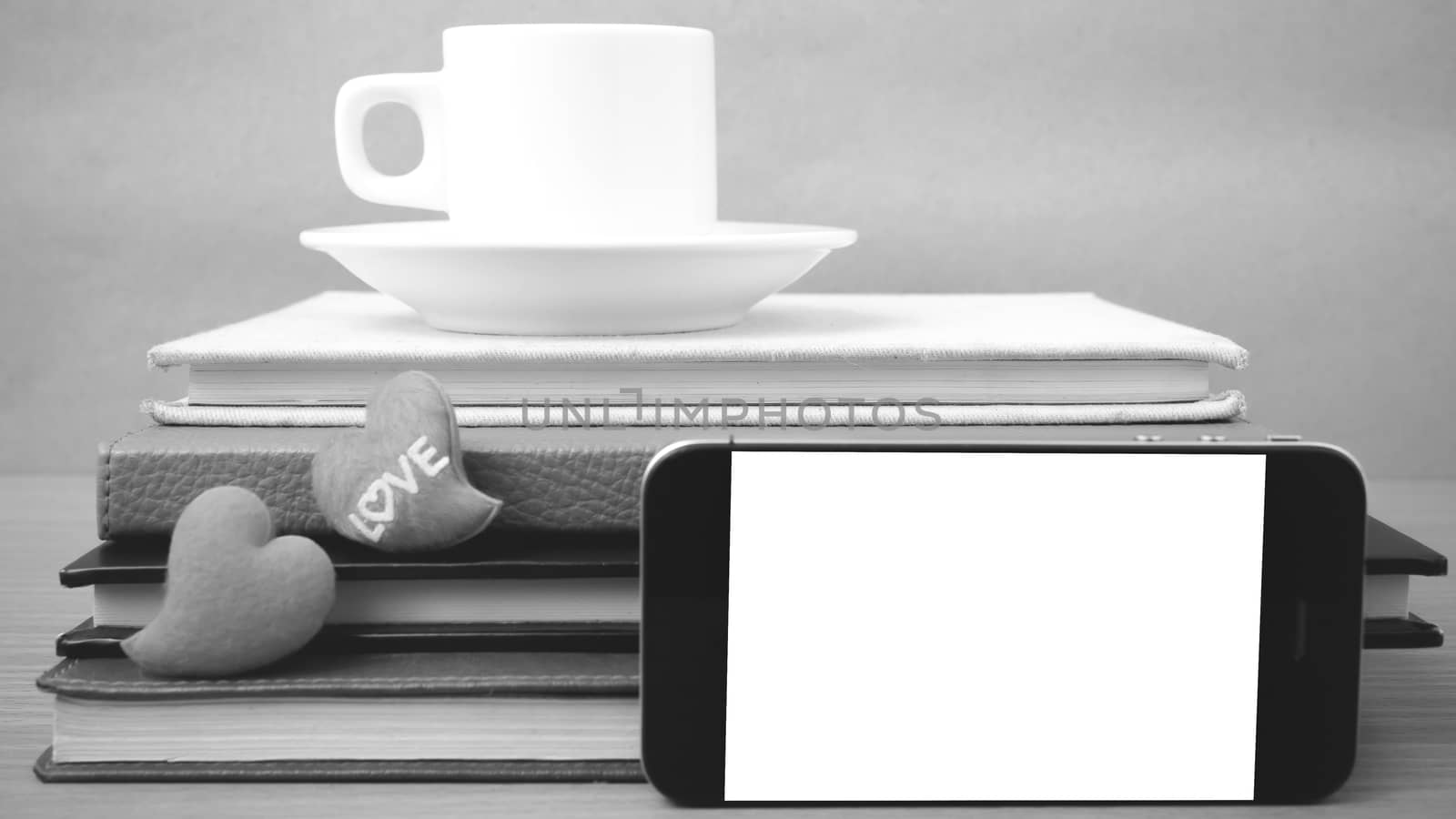 coffee,phone,stack of book and heart on wood table background black and white color