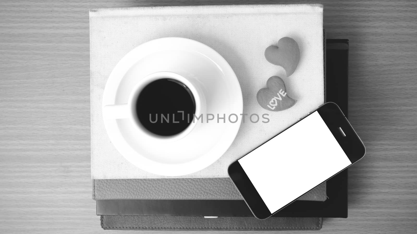 coffee,phone,stack of book and heart on wood table background black and white color