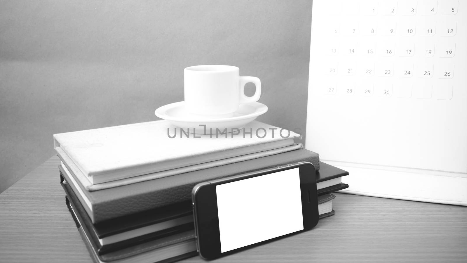 coffee,phone,stack of book and calendar on wood table background black and white color