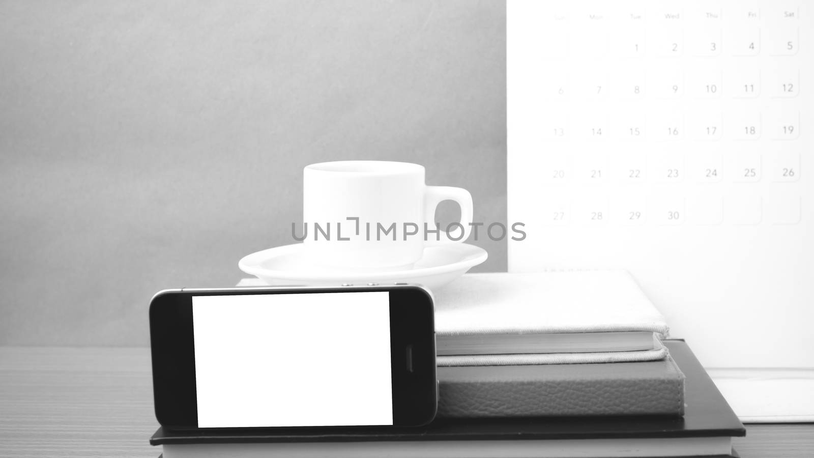 coffee,phone,stack of book and calendar on wood table background black and white color