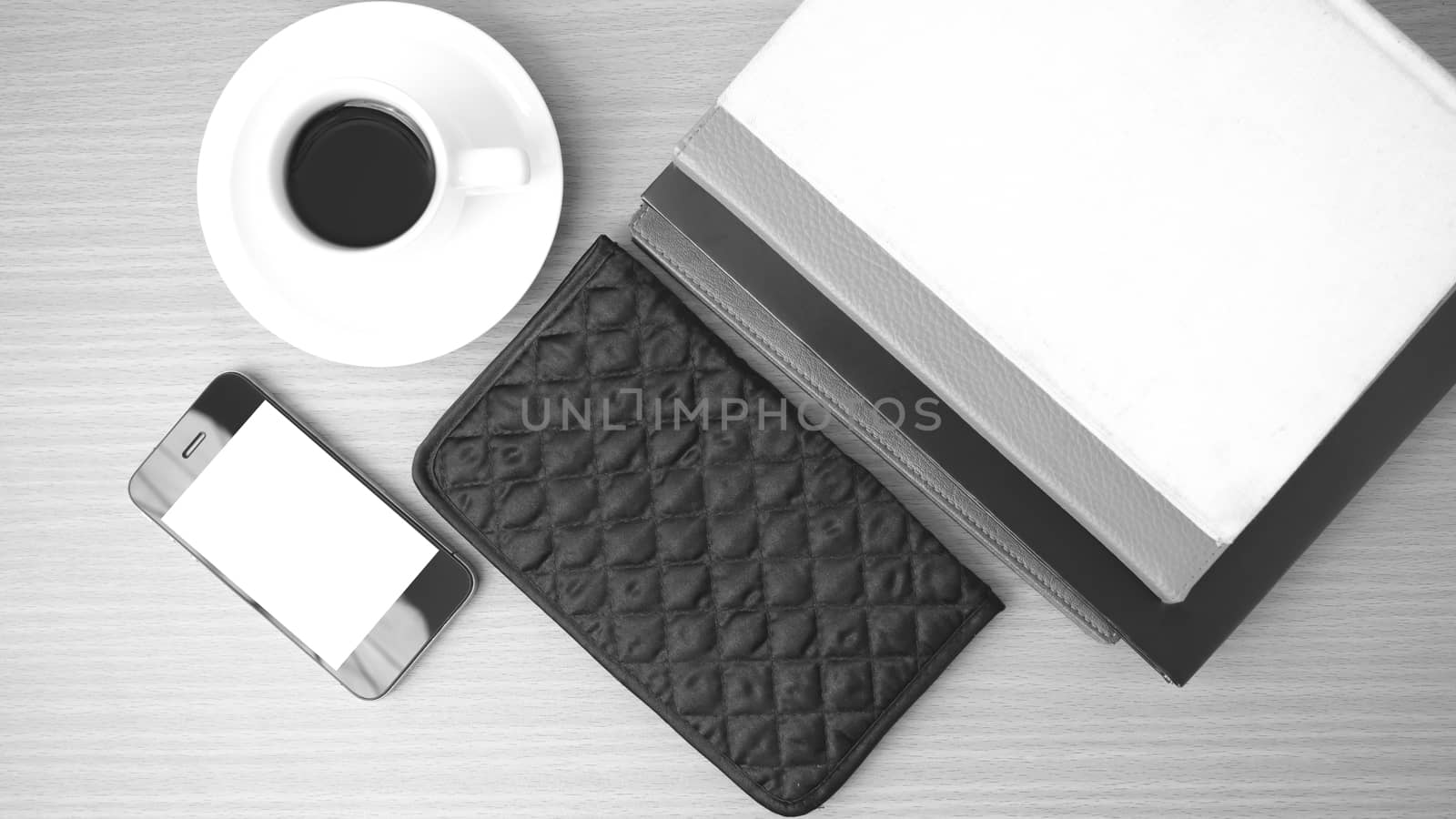 coffee,phone,stack of book and wallet on wood table background black and white color