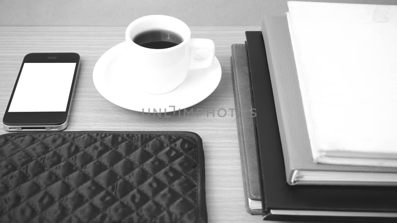 coffee,phone,stack of book and wallet on wood table background black and white color