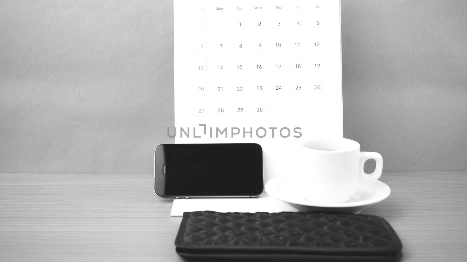 coffee,phone,wallet and canlendar on wood table background black and white color