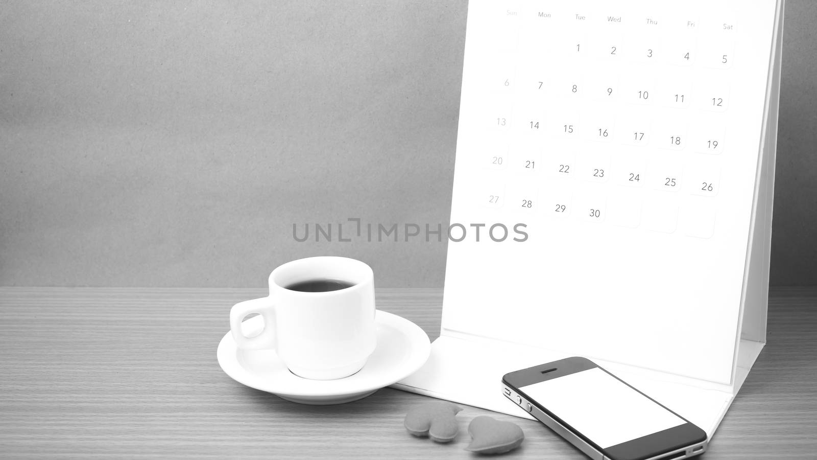 coffee,phone,calendar and heart on wood table background black and white color