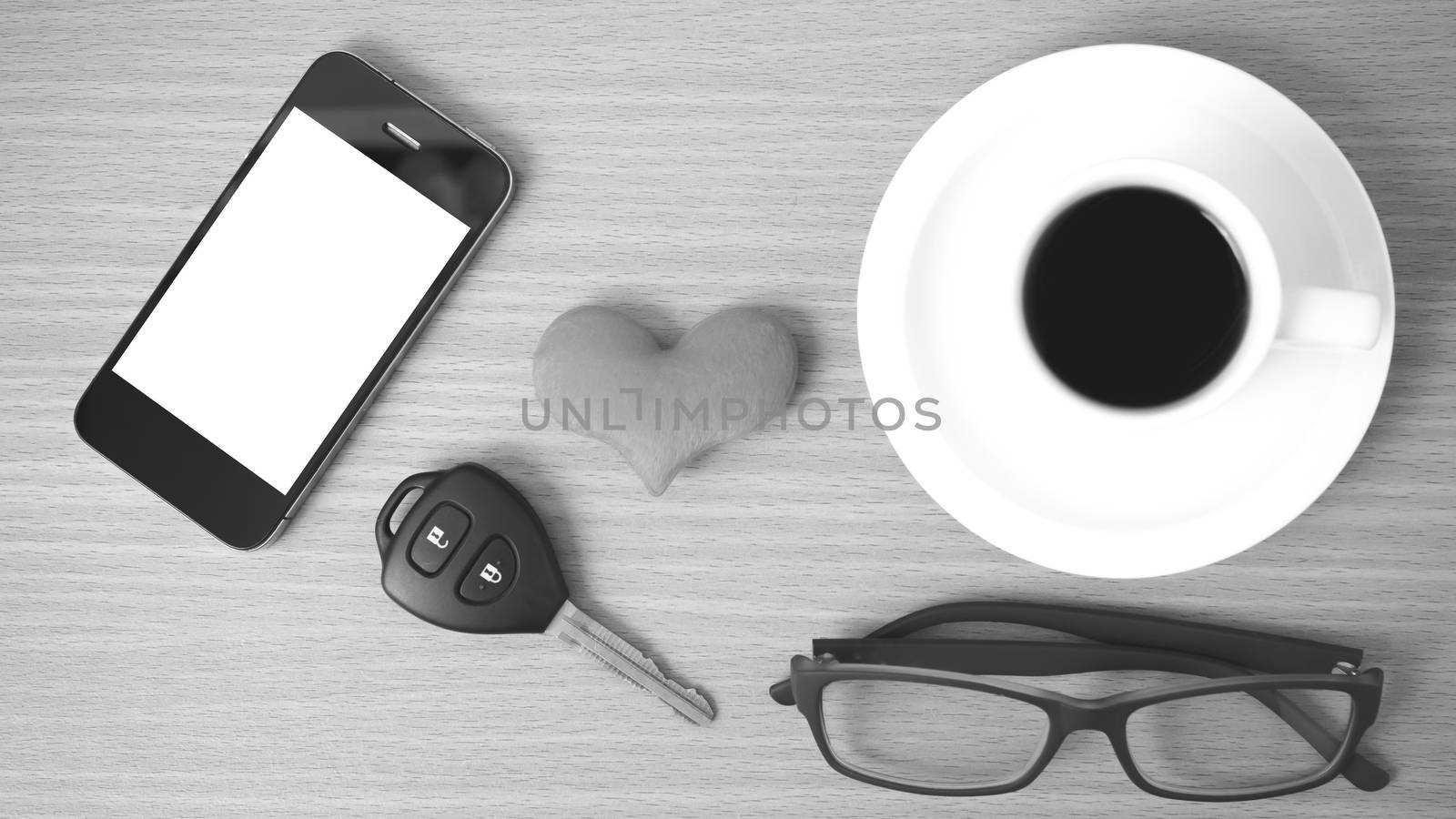 coffee,phone,eyeglasses and car key on wood table background black and white color