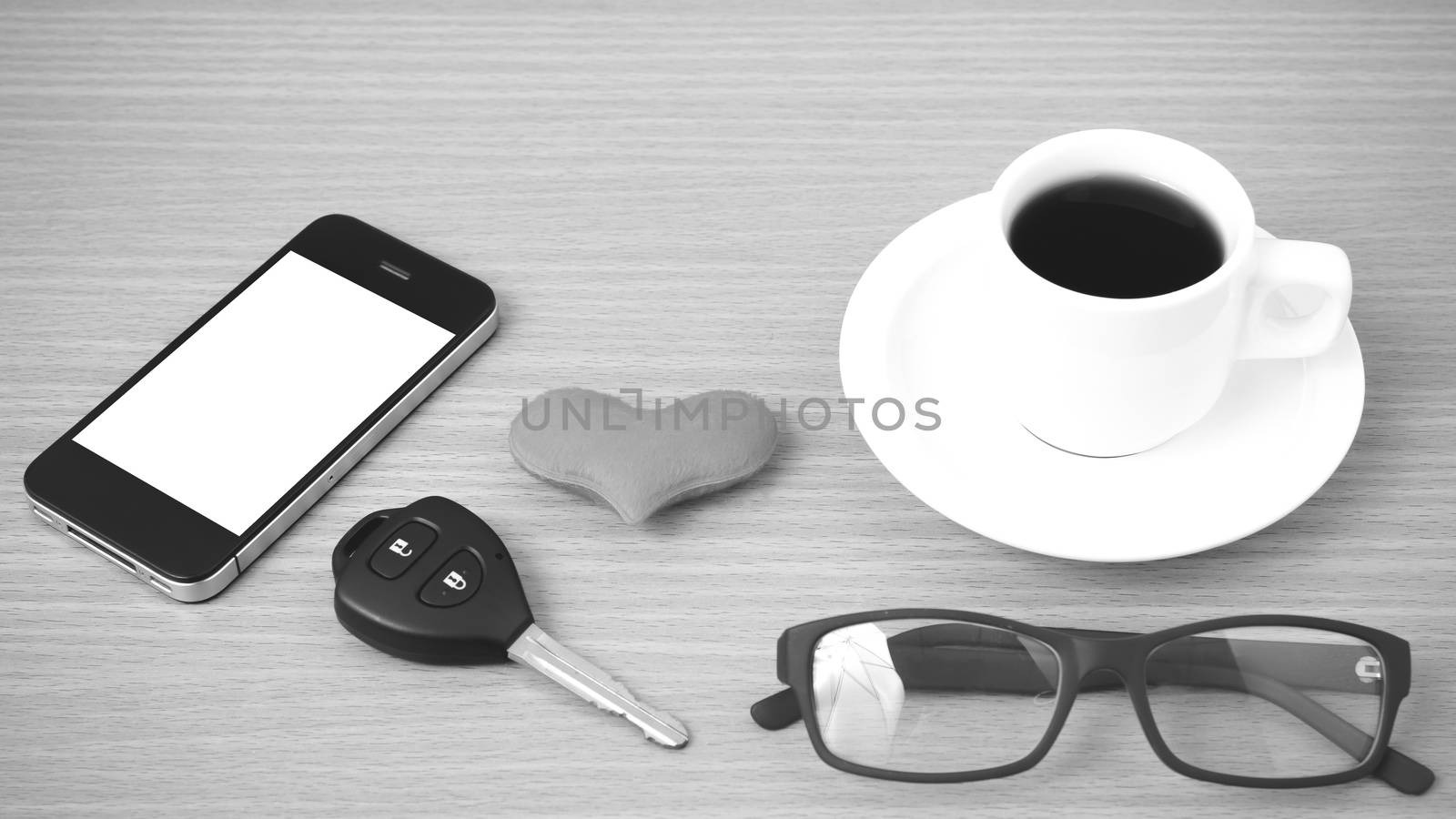 coffee,phone,eyeglasses and car key on wood table background black and white color