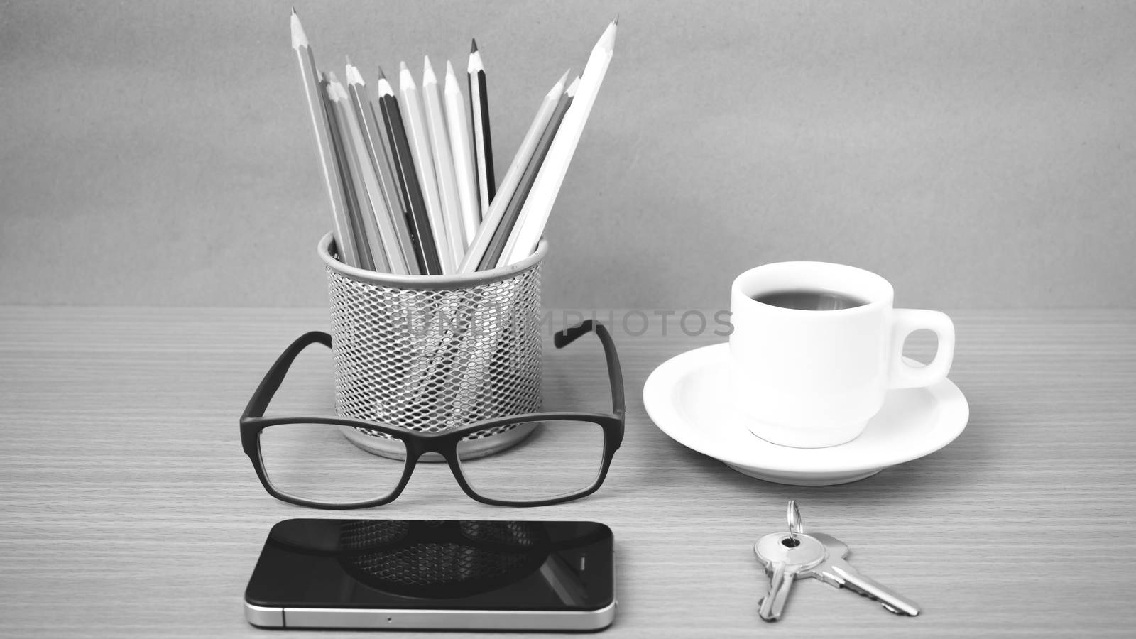 coffee,phone,eyeglasses,color pencil and key on wood table background black and white color