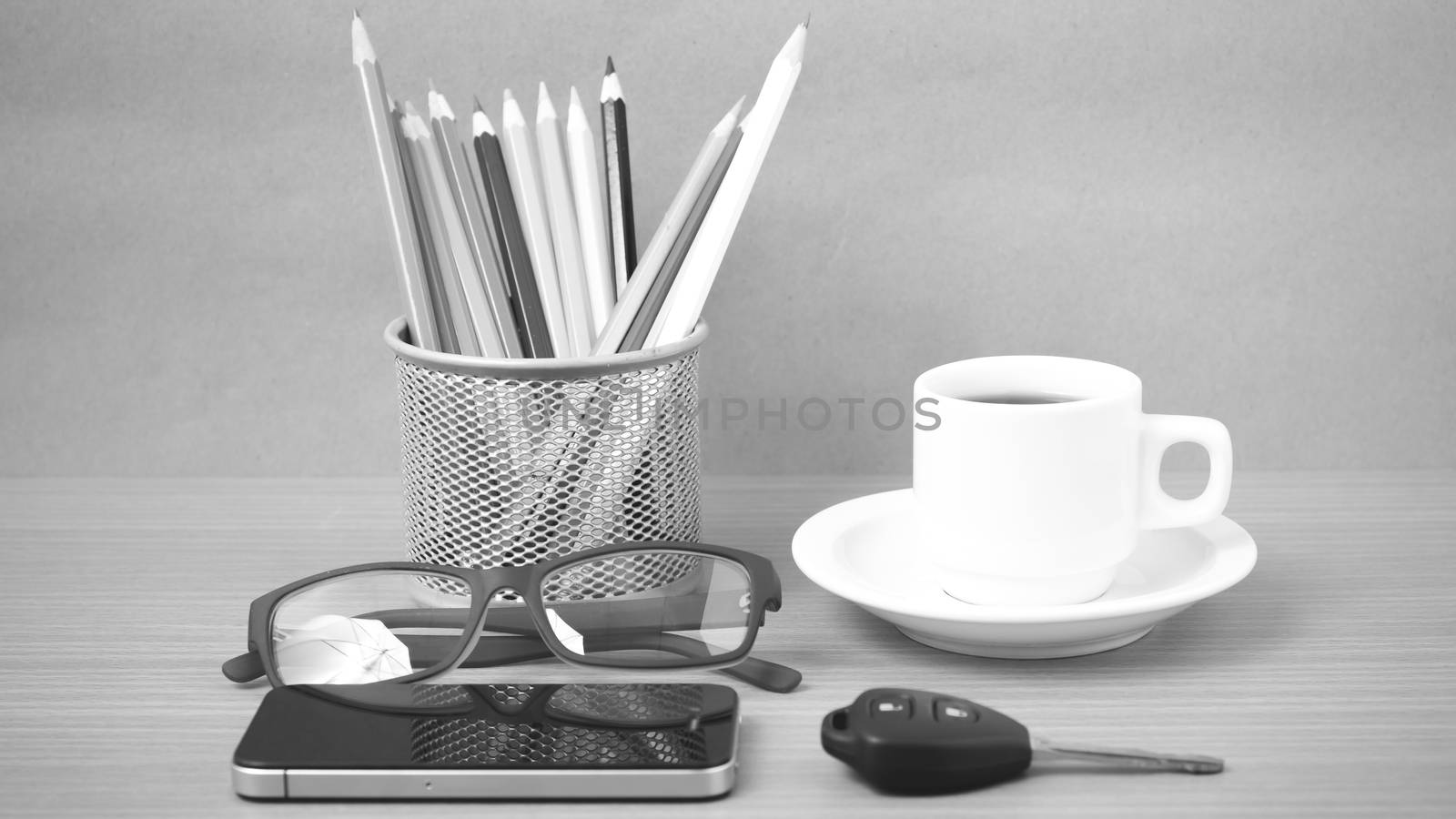 coffee,phone,eyeglasses,color pencil and car key on wood table background black and white color