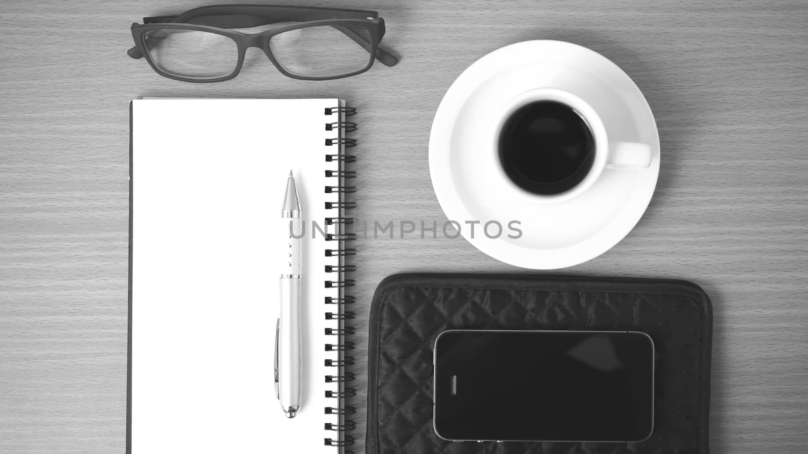 coffee,phone,eyeglasses,notepad and wallet on wood table background black and white color