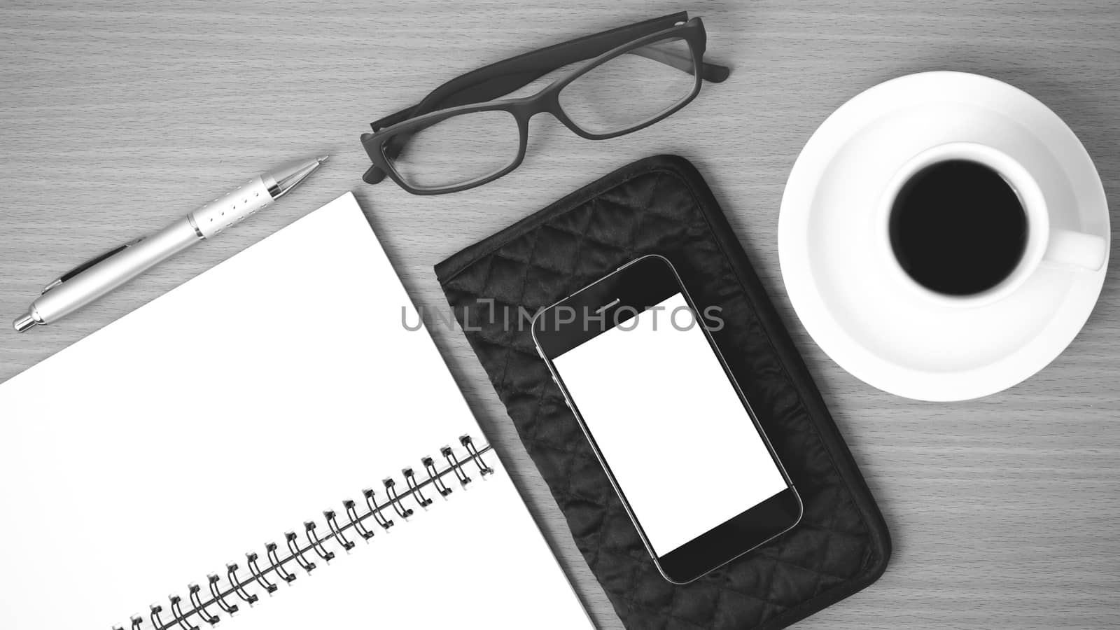 coffee,phone,eyeglasses,notepad and wallet on wood table background black and white color