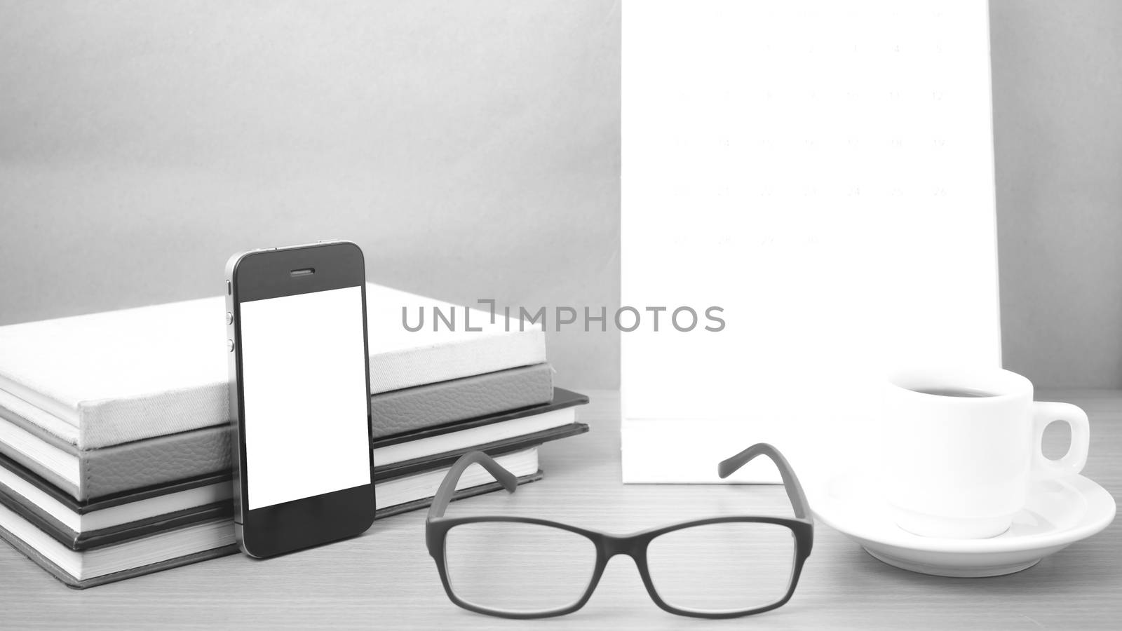 coffee,phone,eyeglasses,stack of book and calendar on wood table background black and white color