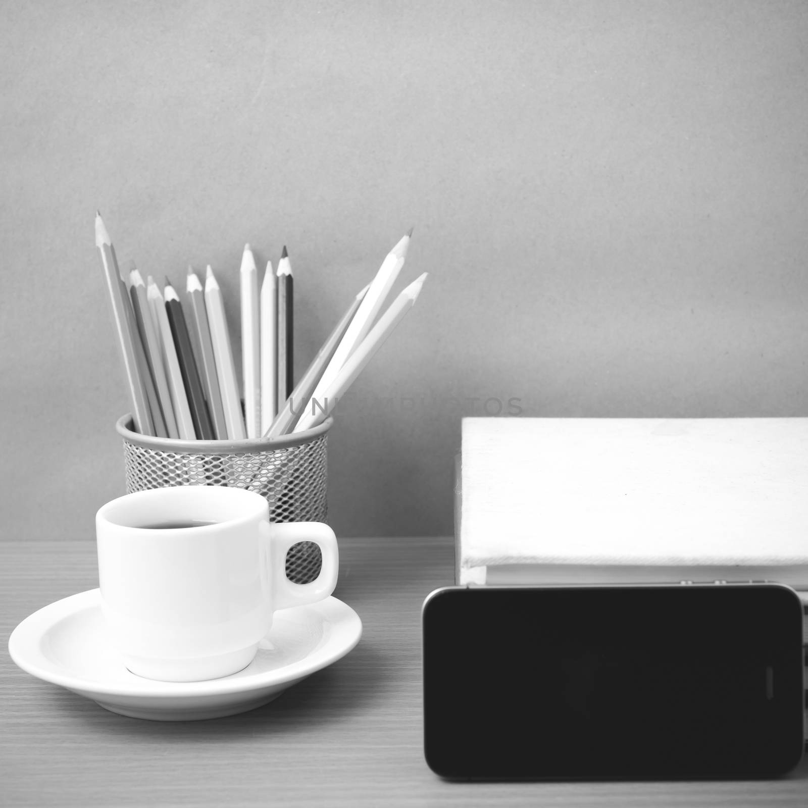 coffee,phone,stack of book and color pencil on wood table background black and white color