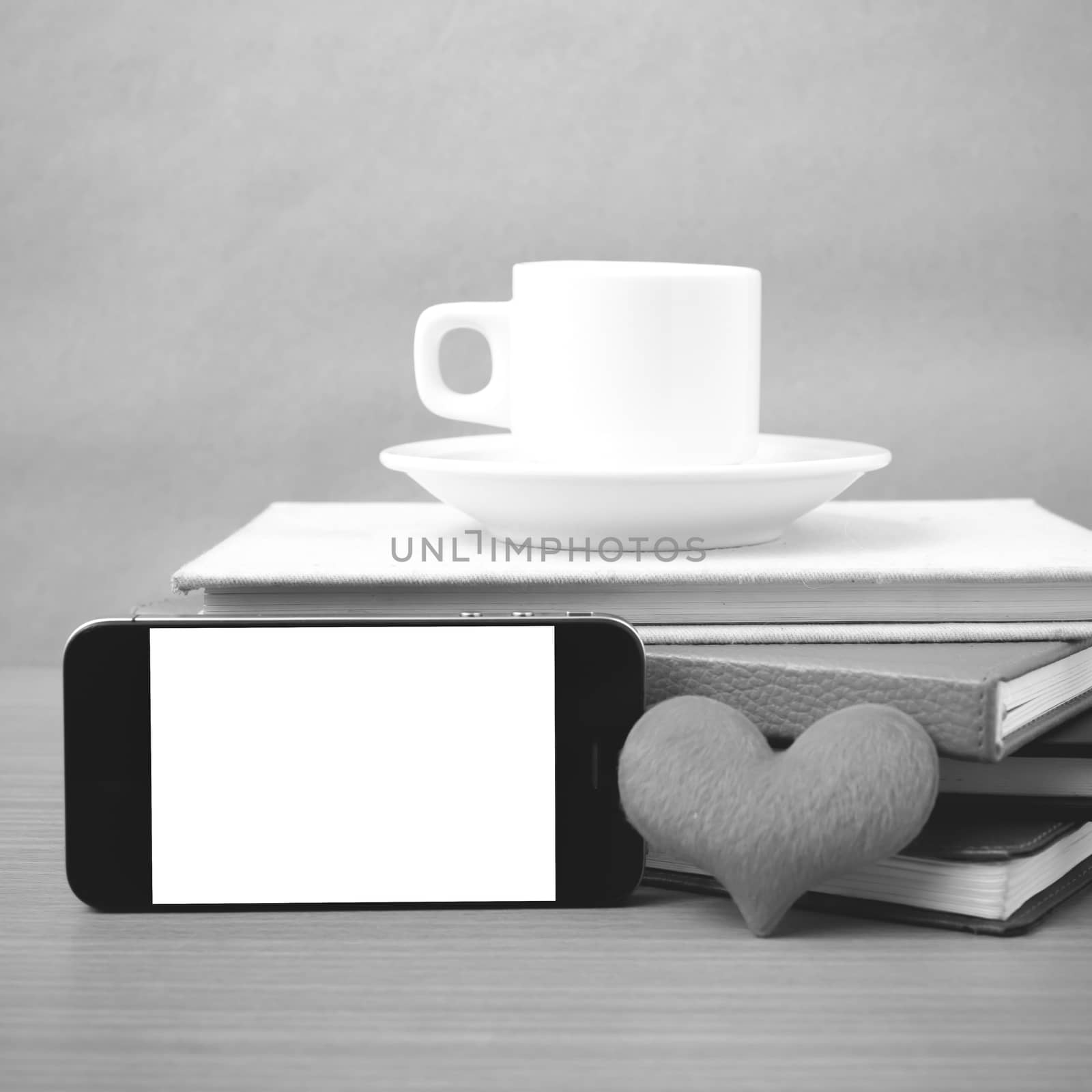 coffee,phone,stack of book and heart on wood table background black and white color