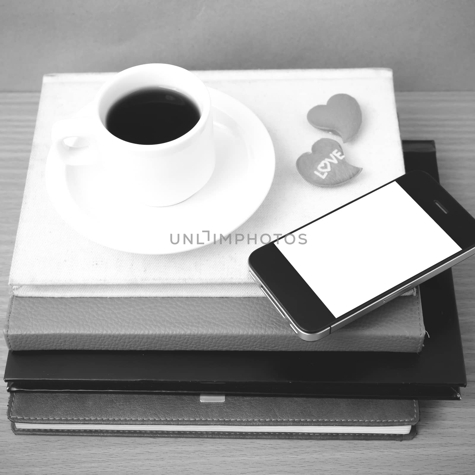 coffee,phone,stack of book and heart on wood table background black and white color