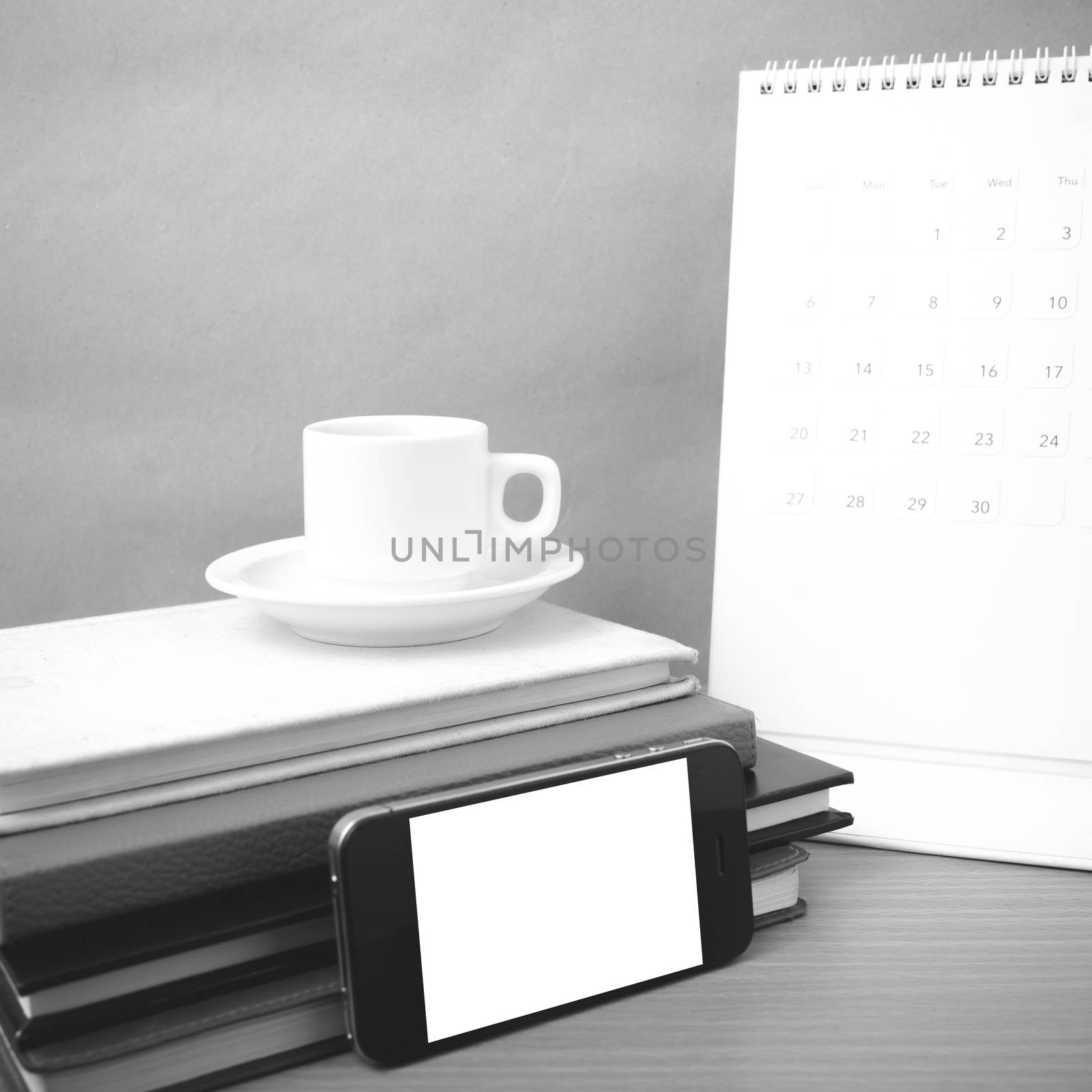 coffee,phone,stack of book and calendar on wood table background black and white color