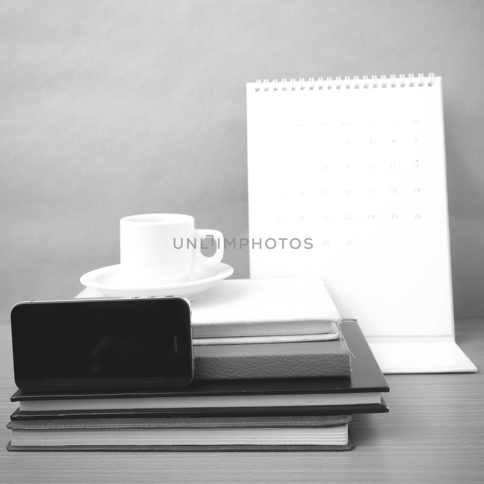 coffee,phone,stack of book and calendar on wood table background black and white color