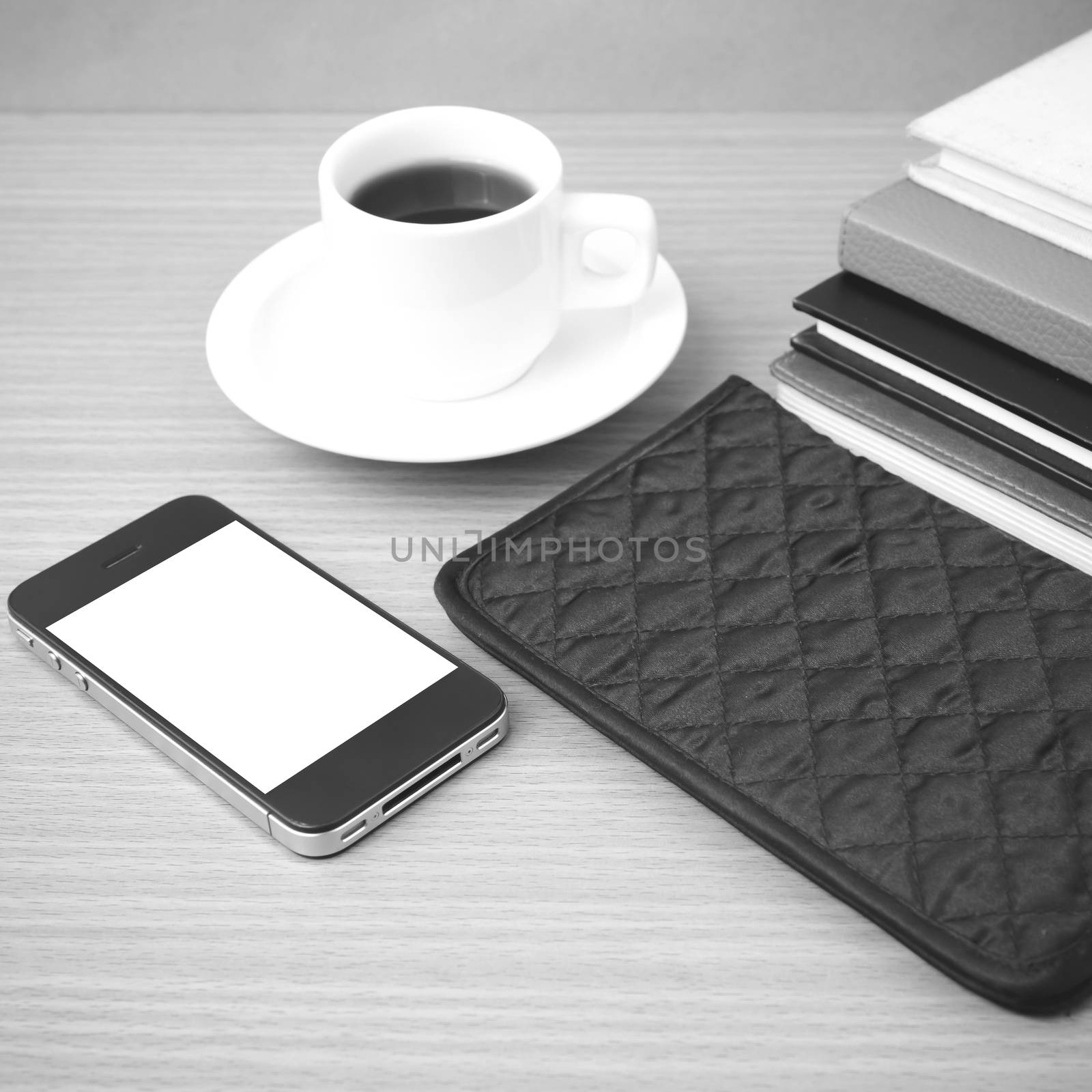 coffee,phone,stack of book and wallet on wood table background black and white color