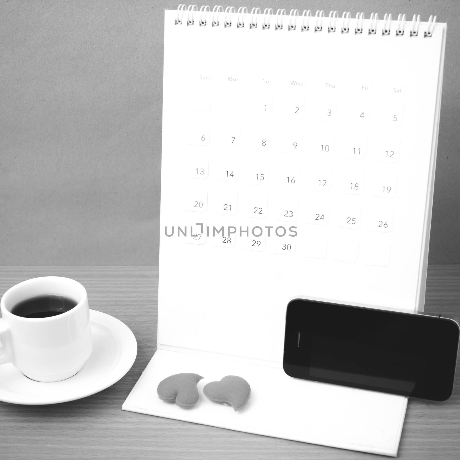 coffee,phone,calendar and heart on wood table background black and white color