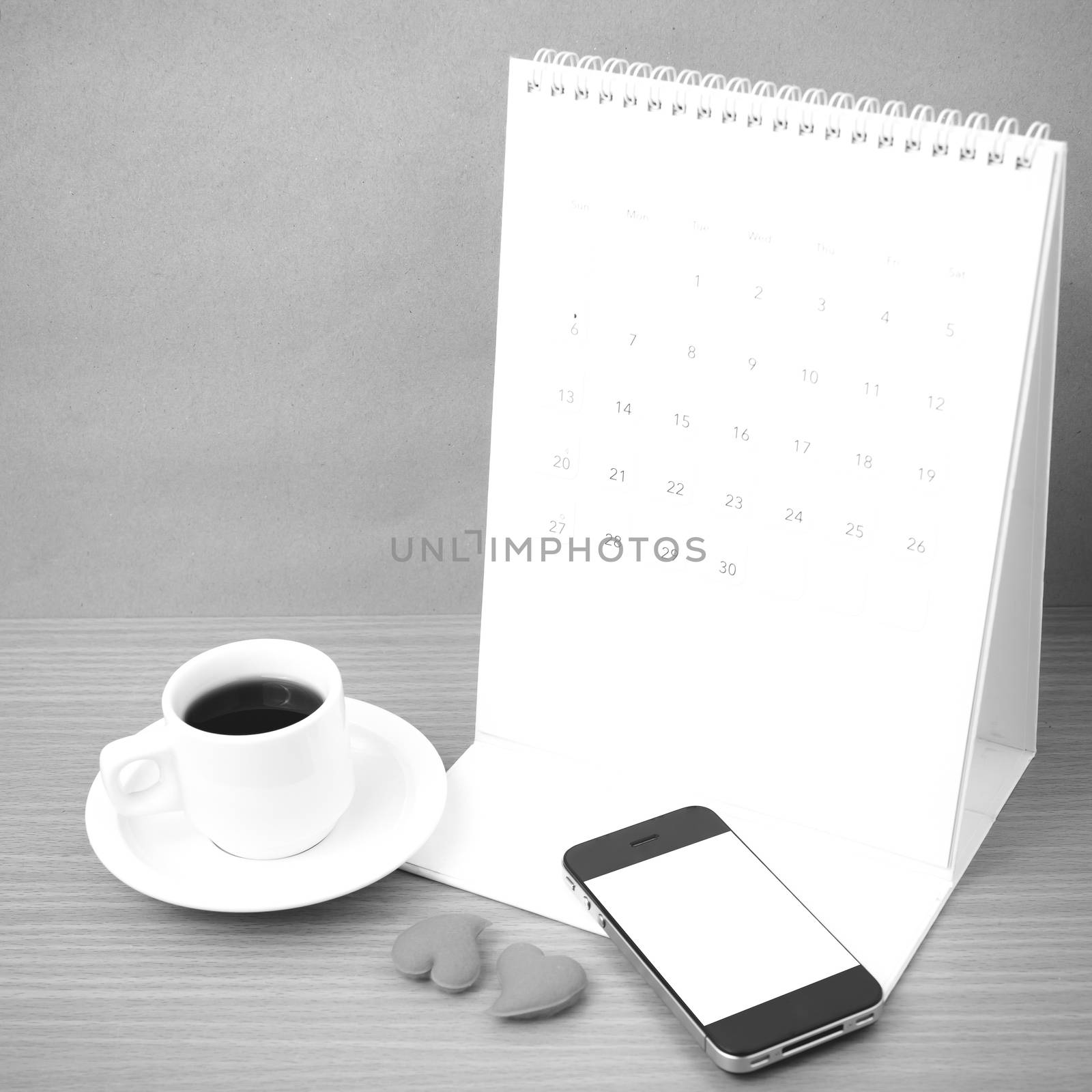 coffee,phone,calendar and heart on wood table background black and white color