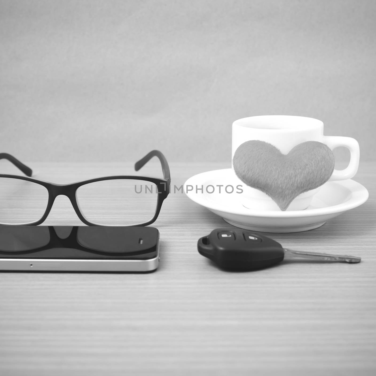 coffee,phone,eyeglasses and car key on wood table background black and white color