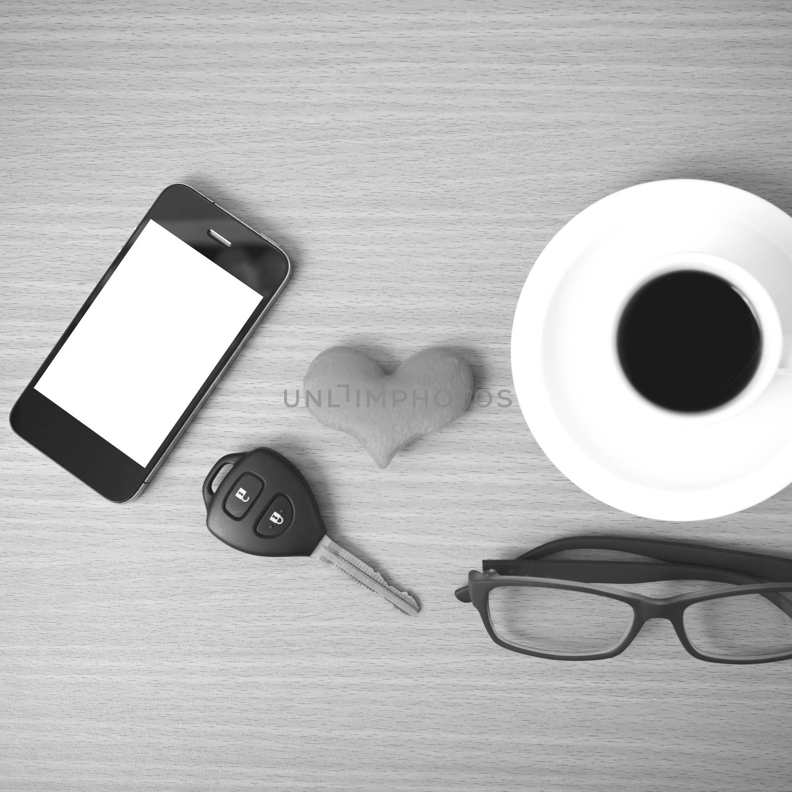 coffee,phone,eyeglasses and car key on wood table background black and white color