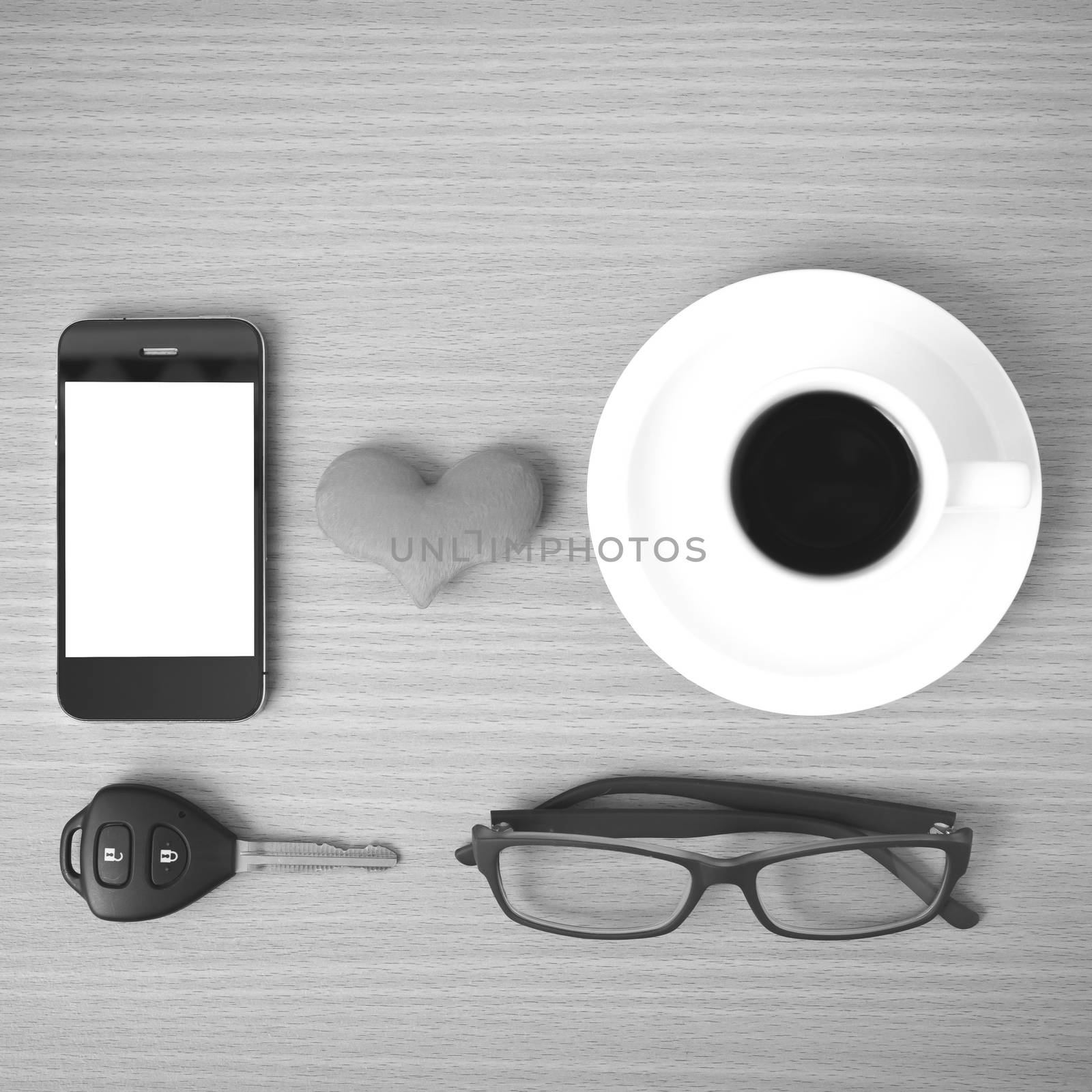 coffee,phone,eyeglasses and car key on wood table background black and white color