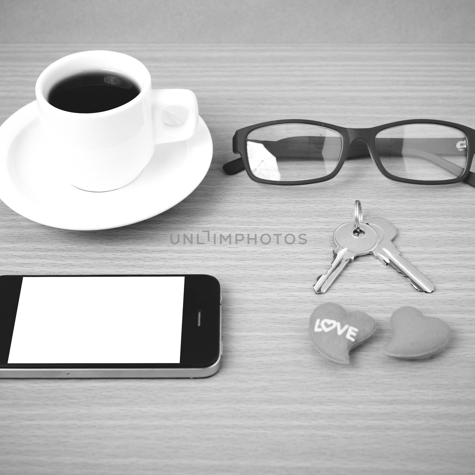 coffee,phone,eyeglasses and key on wood table background black and white color