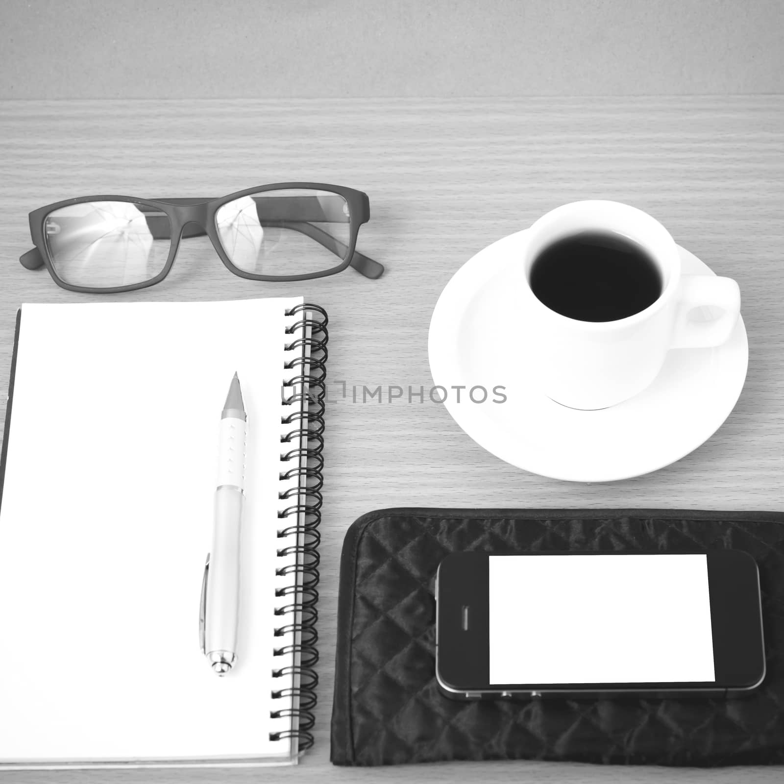 coffee,phone,eyeglasses,notepad and wallet on wood table background black and white color