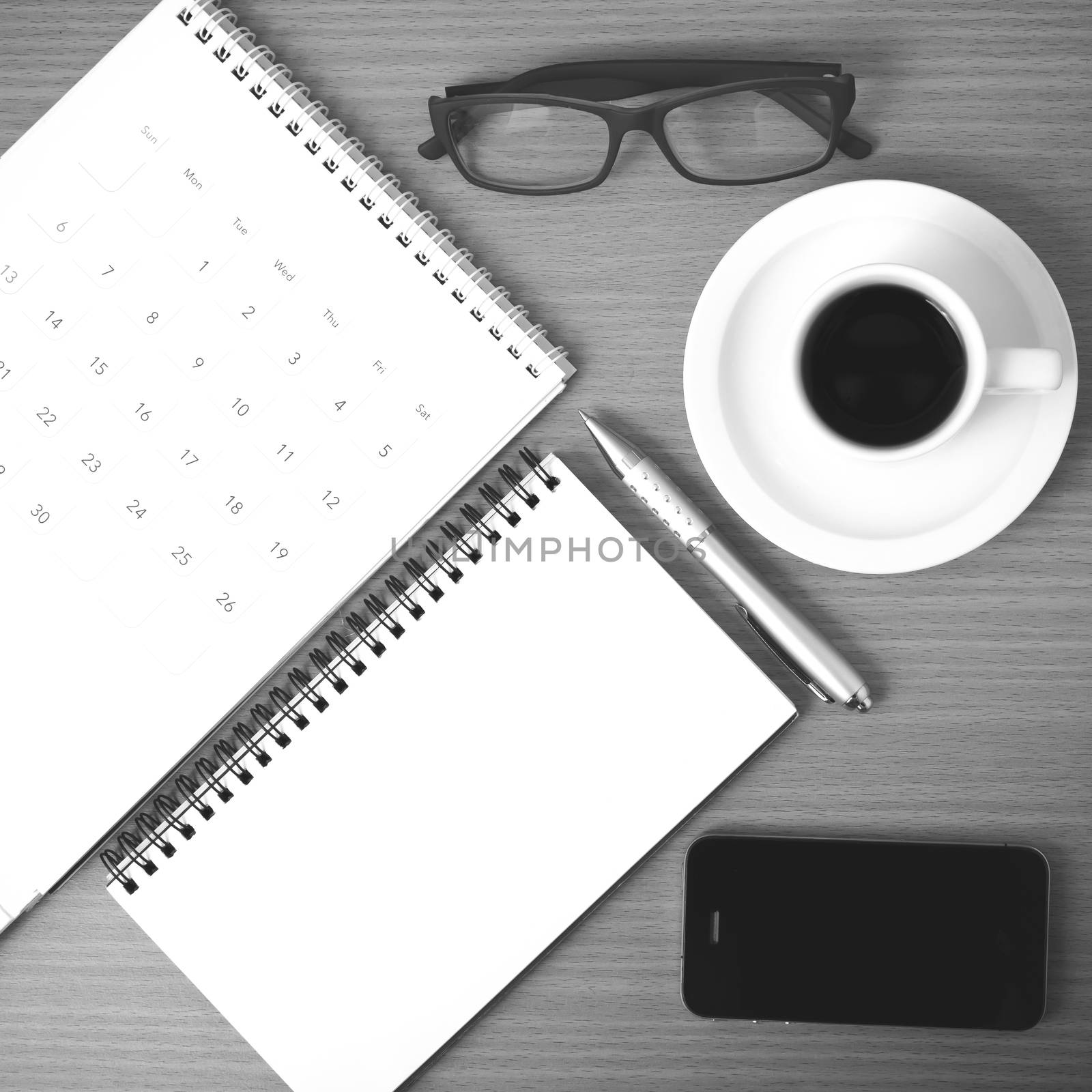 coffee,phone,eyeglasses,notepad and canlendar on wood table background black and white color