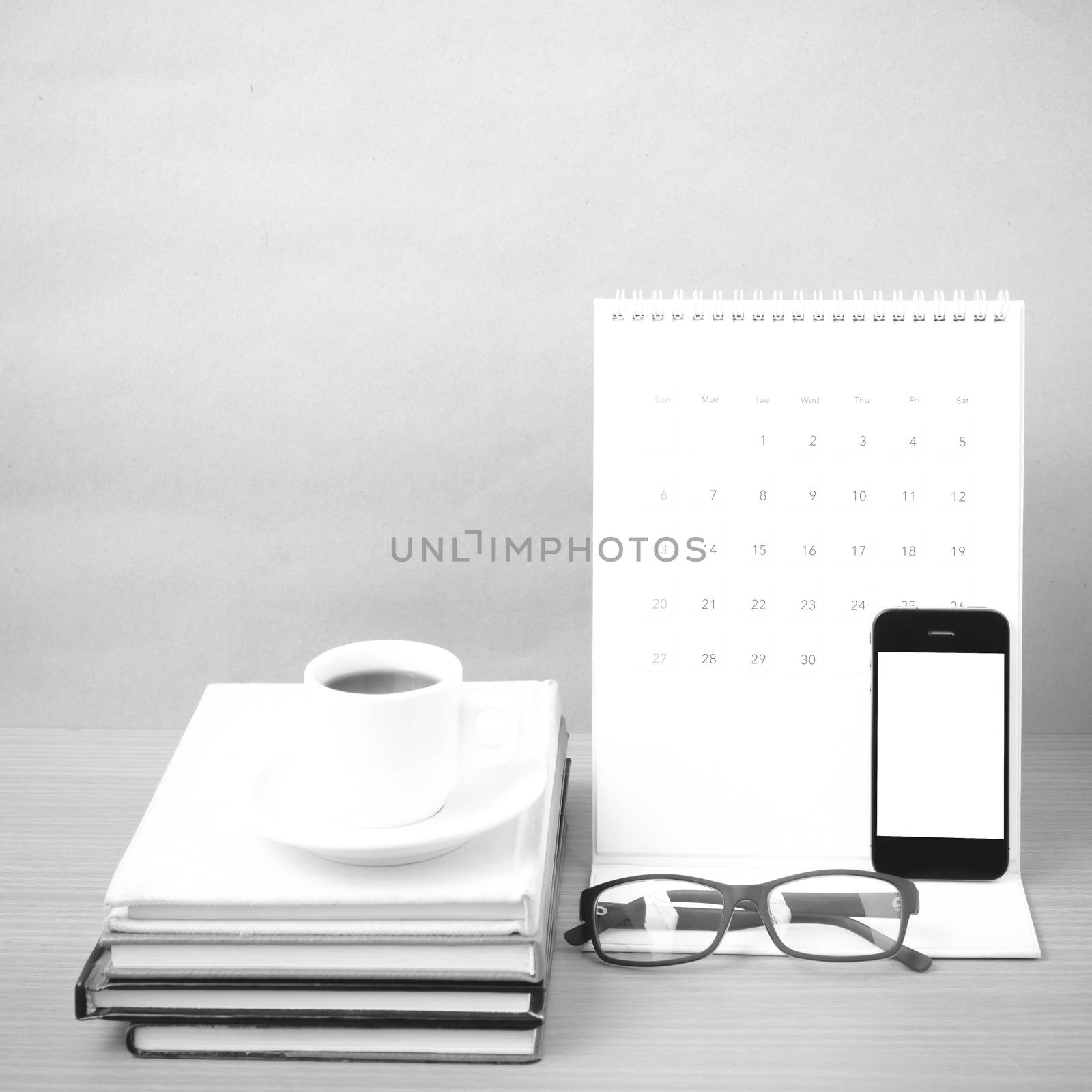 coffee,phone,eyeglasses,stack of book and calendar on wood table background black and white color
