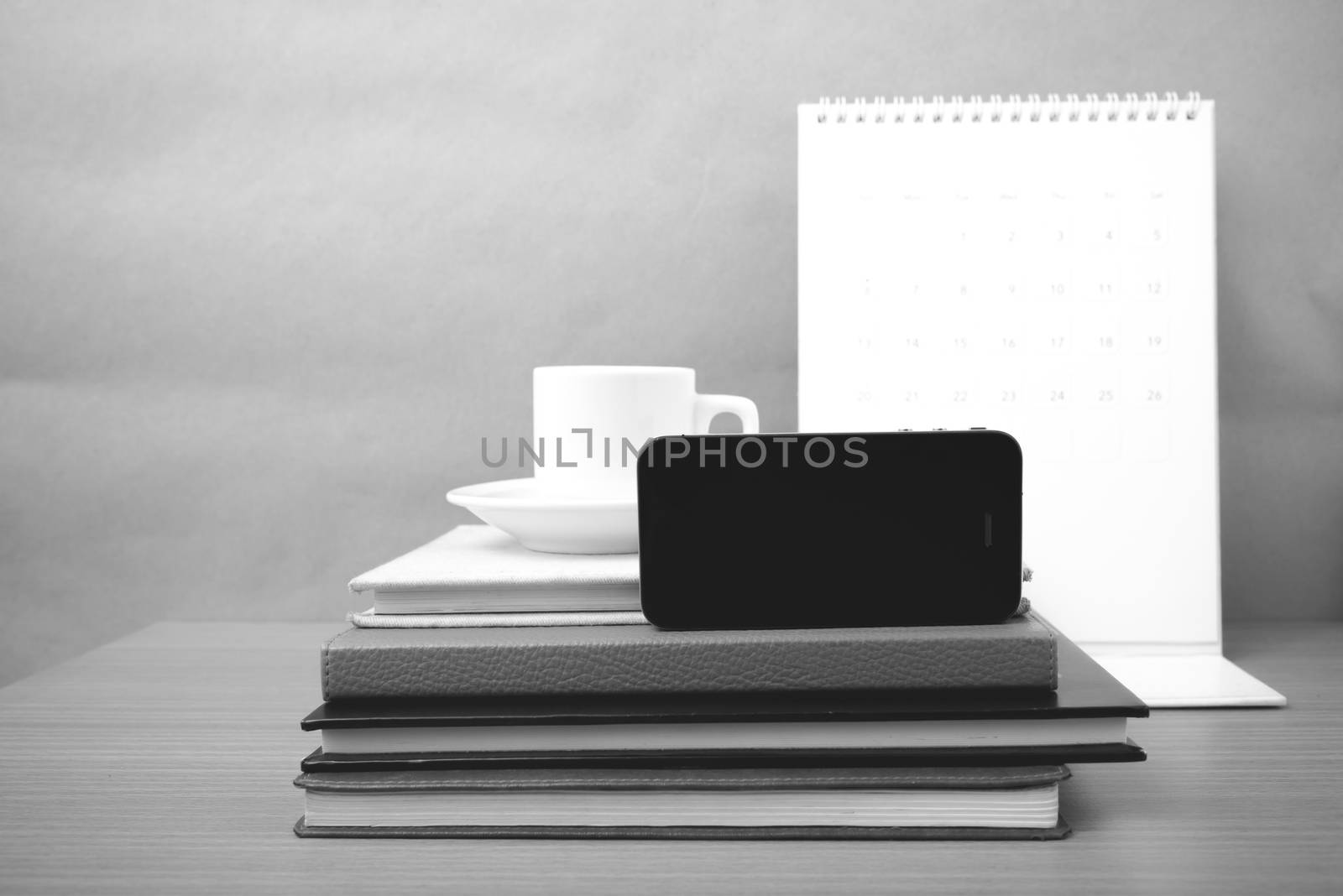 coffee,phone,stack of book and calendar on wood table background black and white color