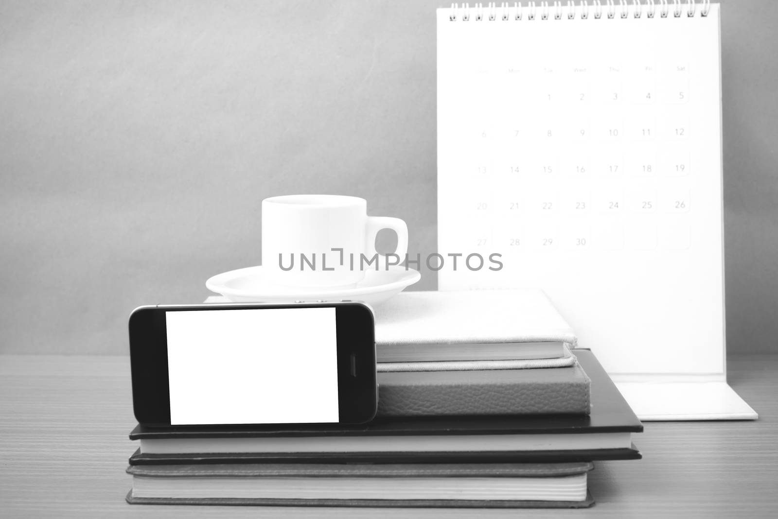 coffee,phone,stack of book and calendar on wood table background black and white color