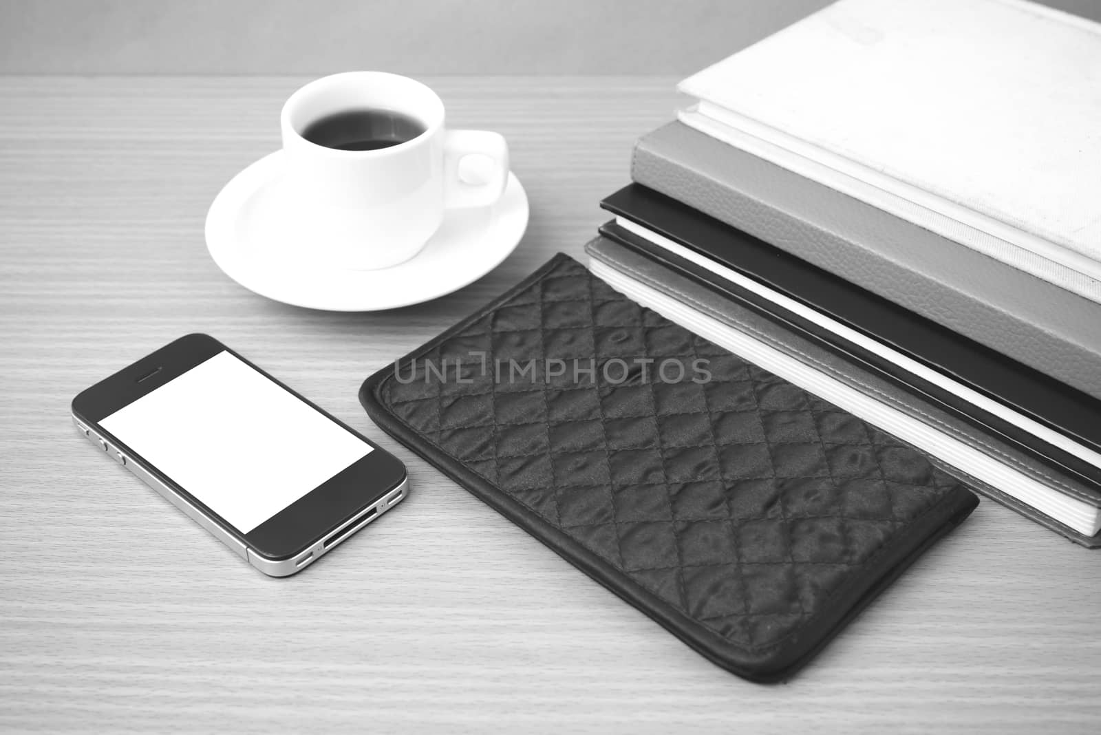 coffee,phone,stack of book and wallet on wood table background black and white color