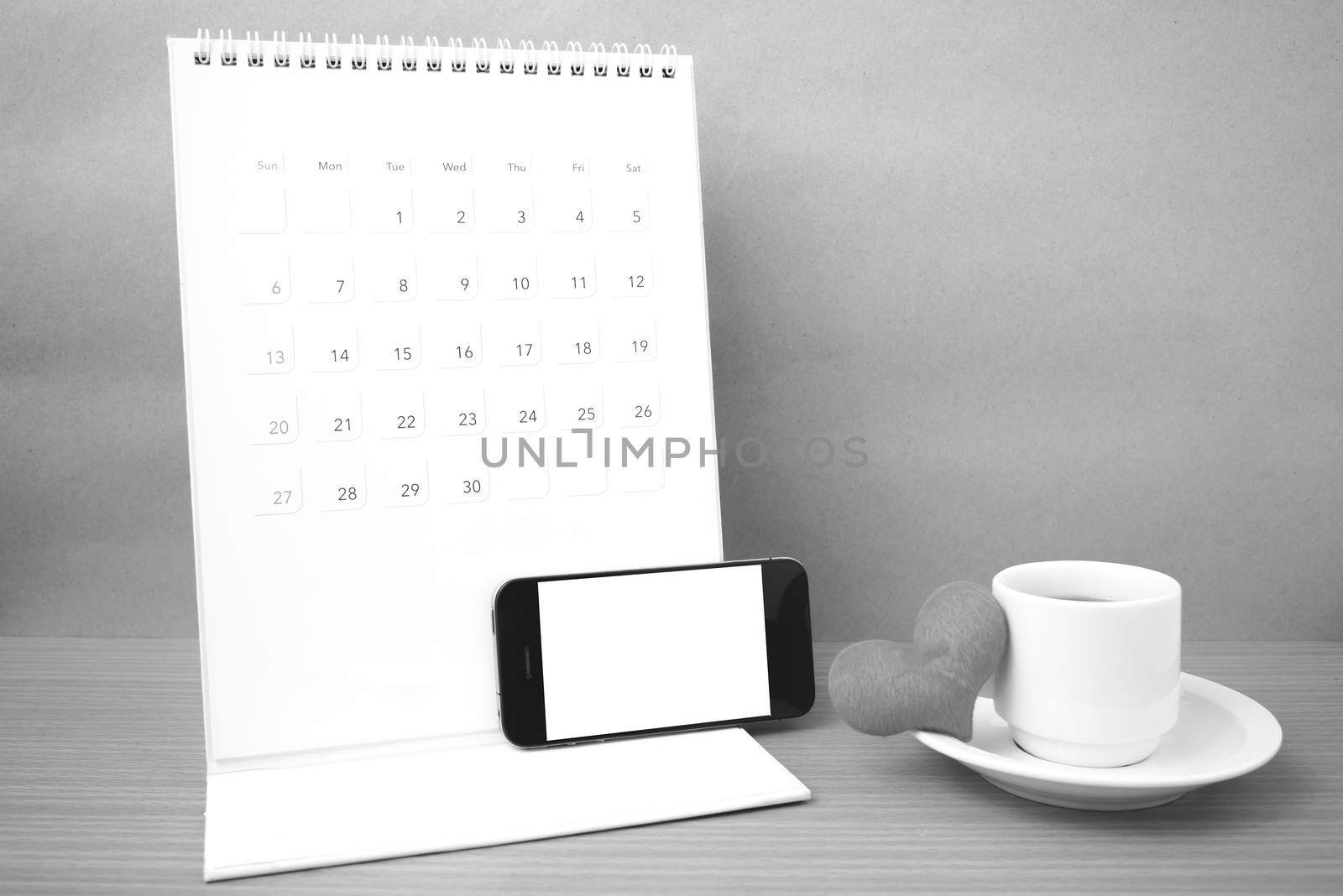 coffee,phone,calendar and heart on wood table background black and white color