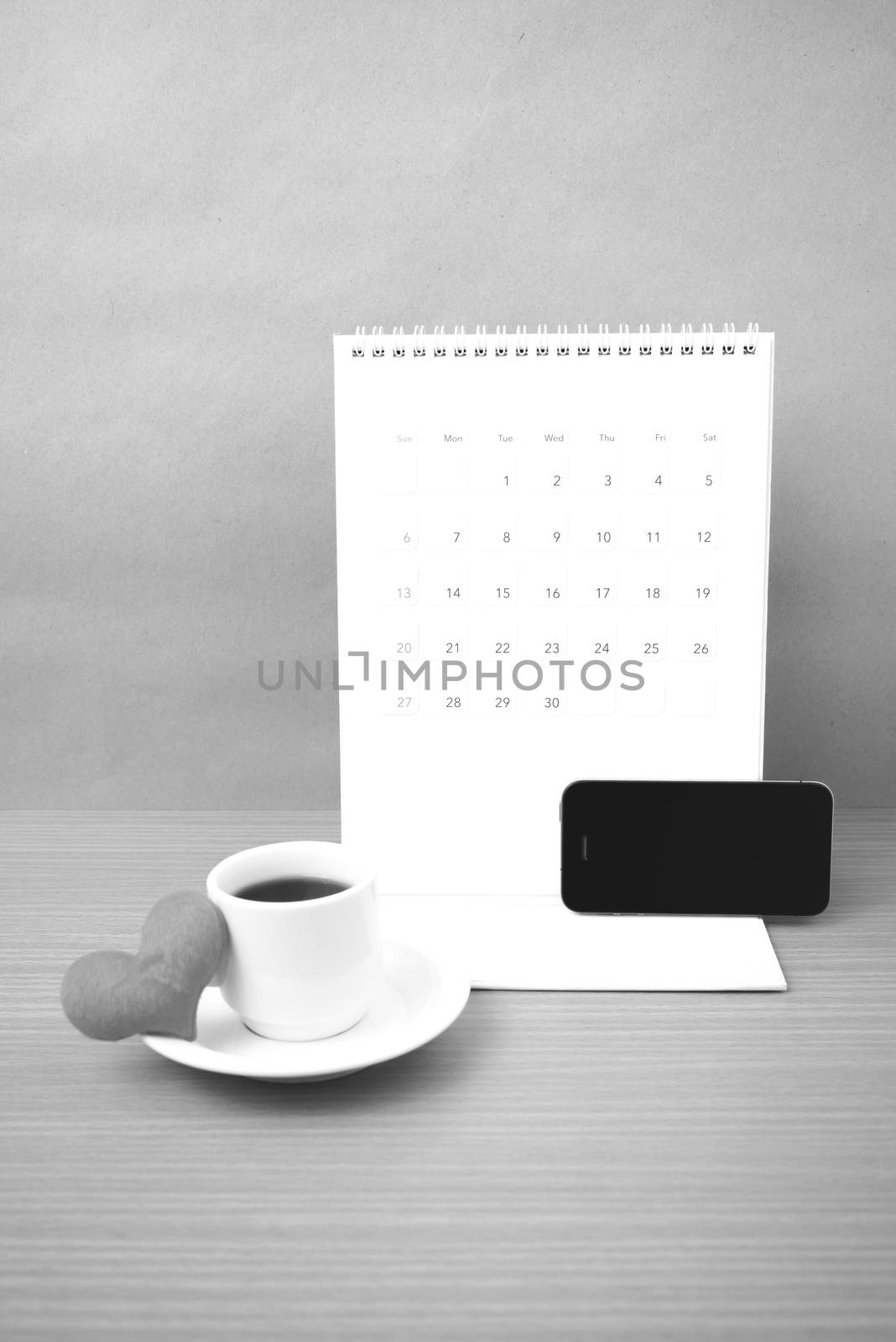 coffee,phone,calendar and heart on wood table background black and white color