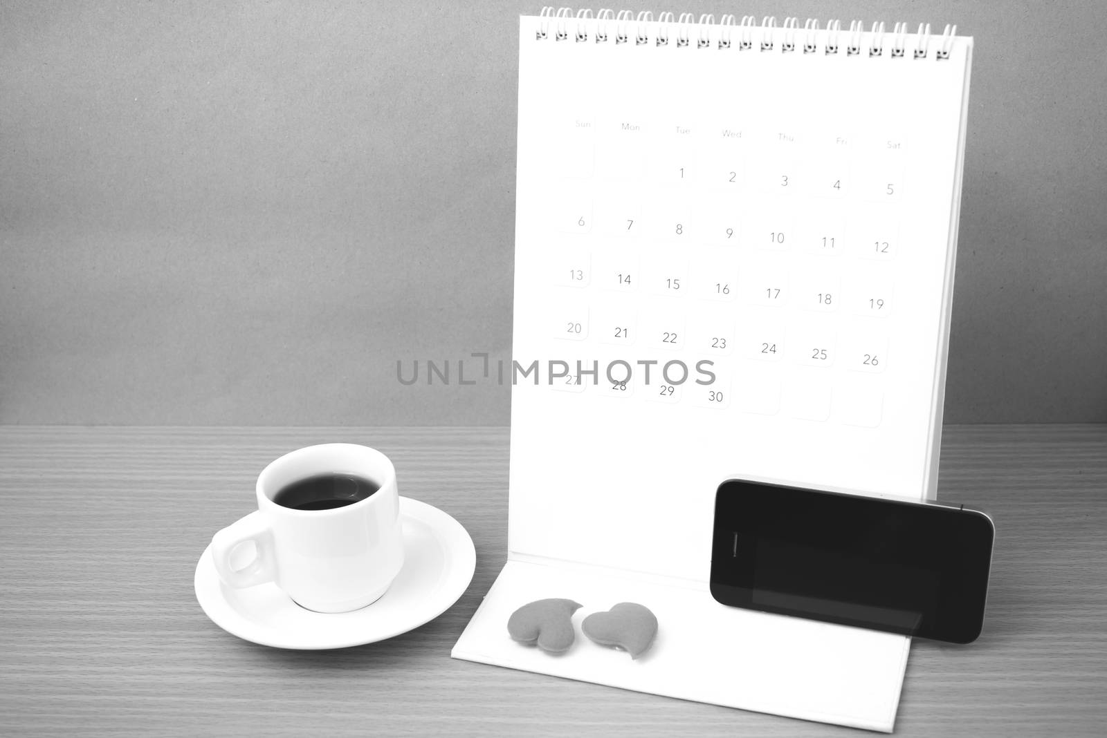 coffee,phone,calendar and heart on wood table background black and white color