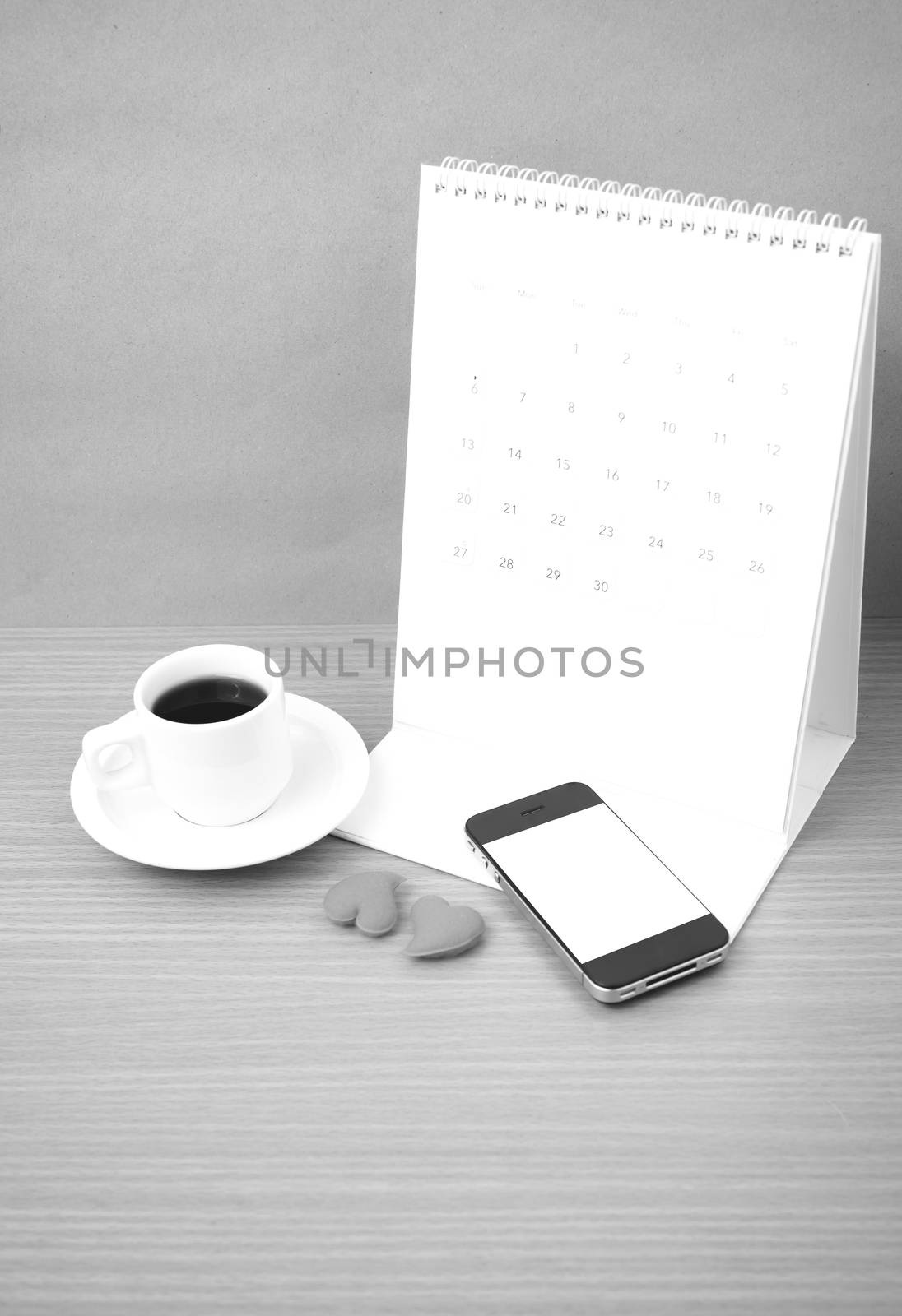 coffee,phone,calendar and heart on wood table background black and white color