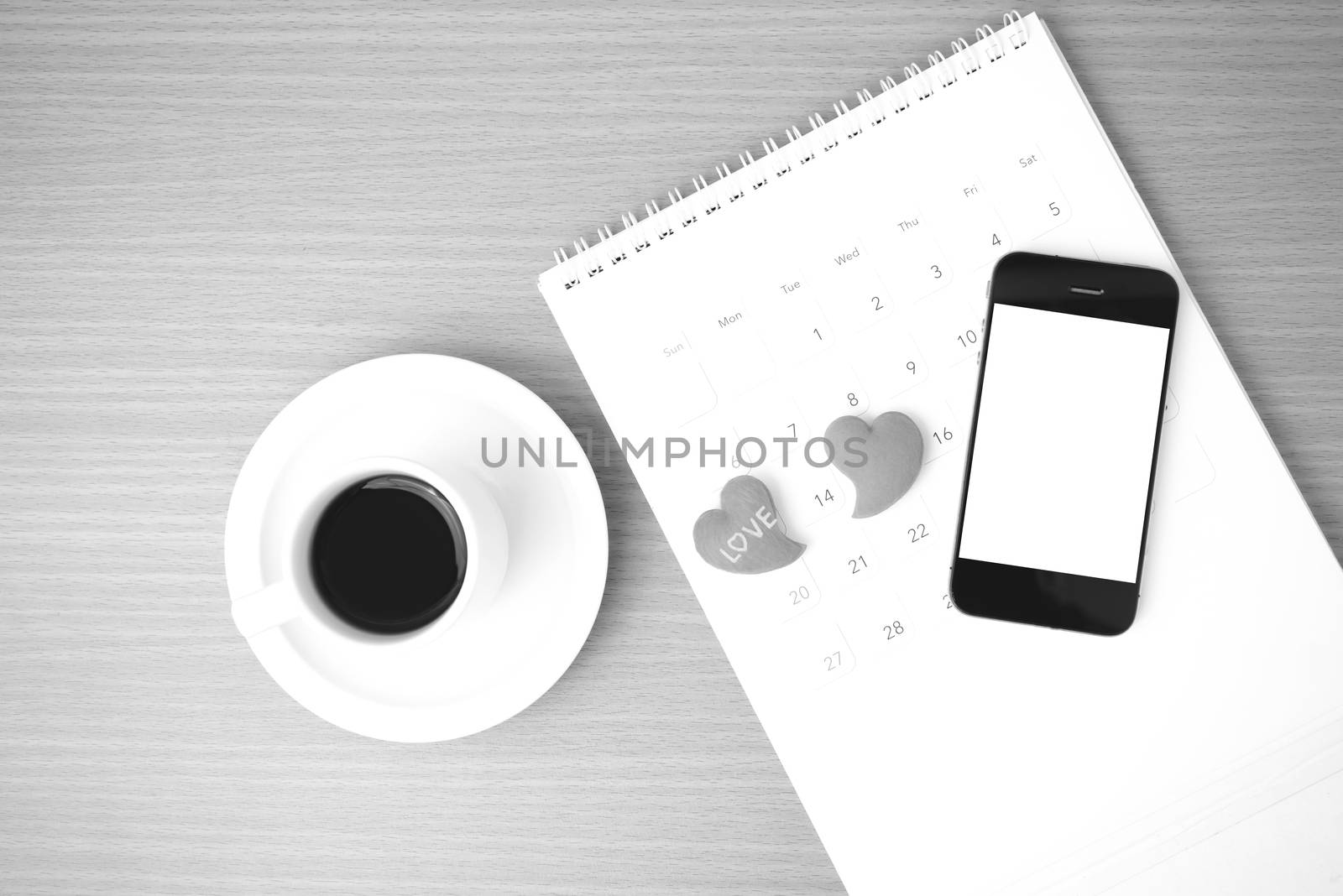 coffee,phone,calendar and heart on wood table background black and white color