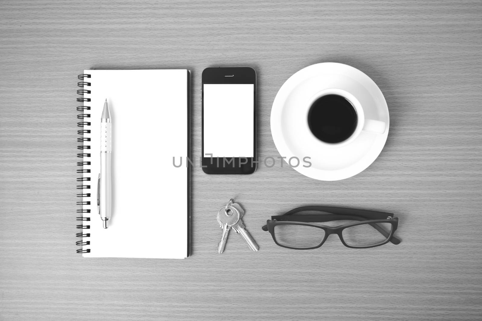 coffee,phone,notepad,eyeglasses and key on wood table background black and white color