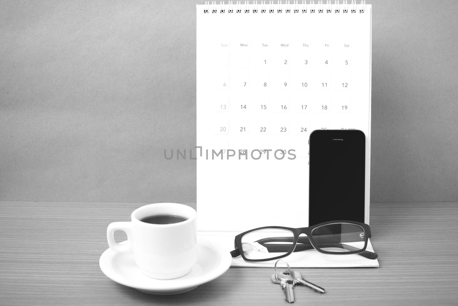 coffee,phone,eyeglasses,calendar and key on wood table background black and white color