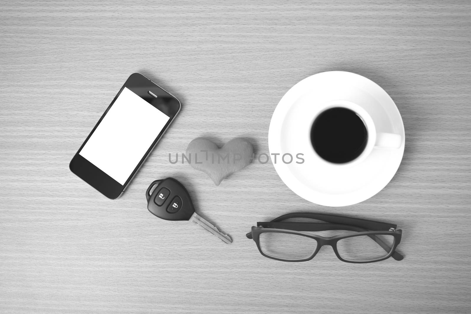 coffee,phone,eyeglasses and car key on wood table background black and white color