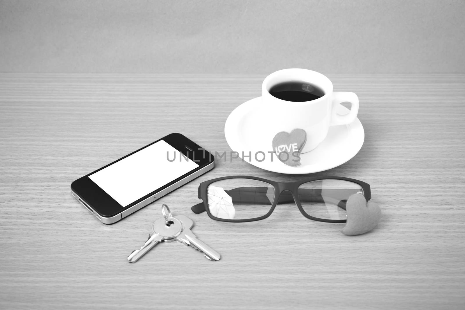 coffee,phone,eyeglasses and key on wood table background black and white color