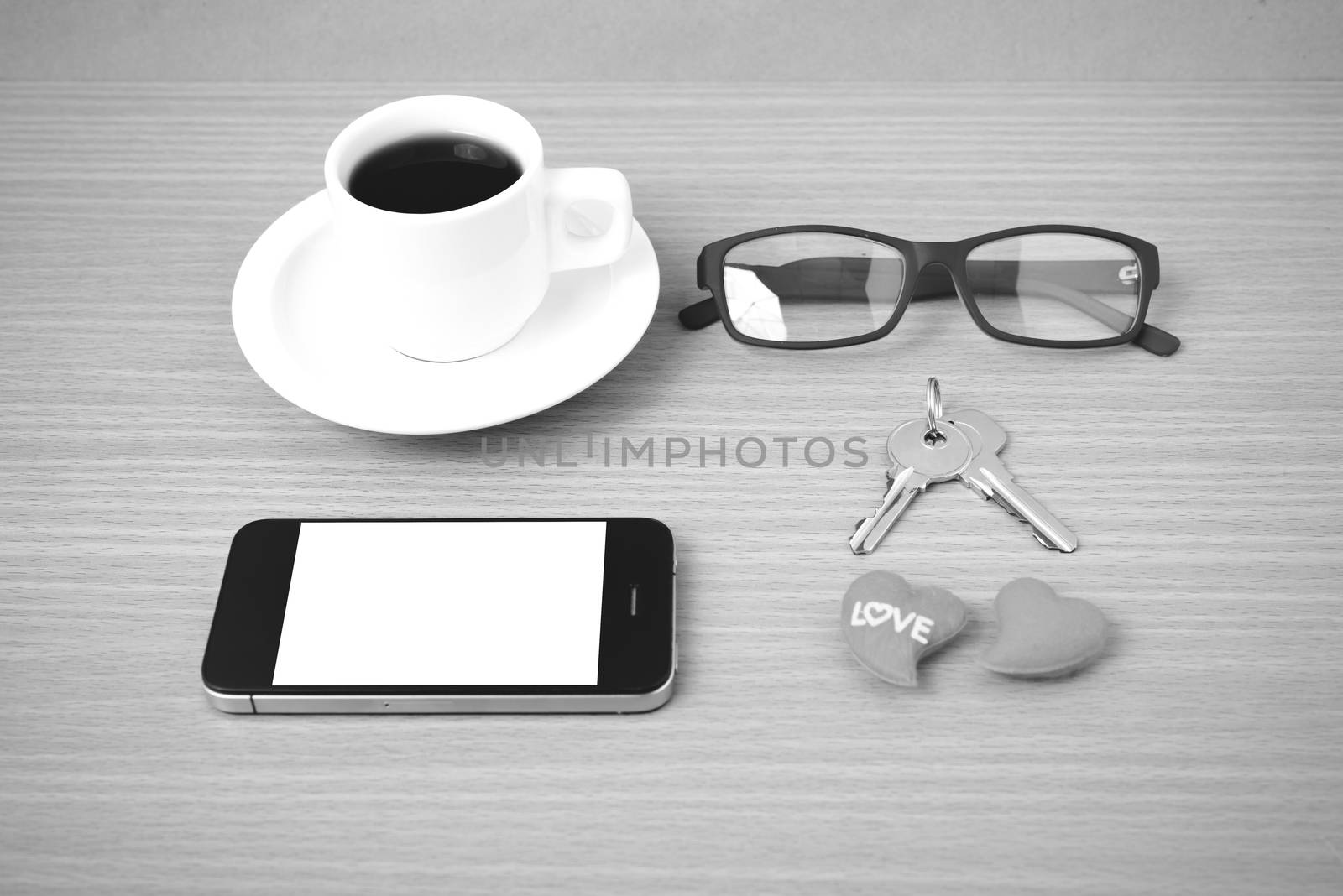 coffee,phone,eyeglasses and key on wood table background black and white color